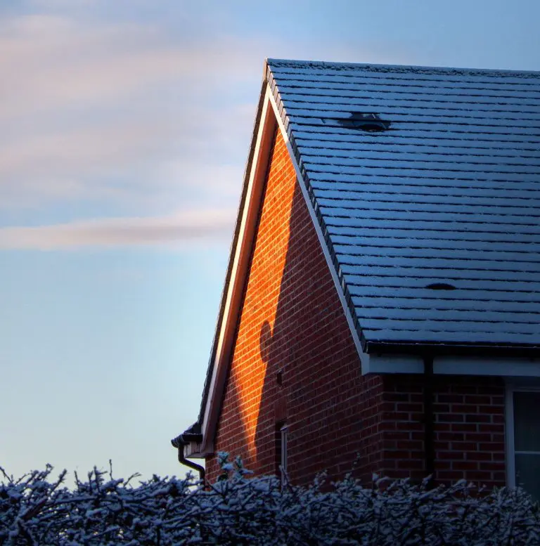 Red brick house with roof covered in snow.
