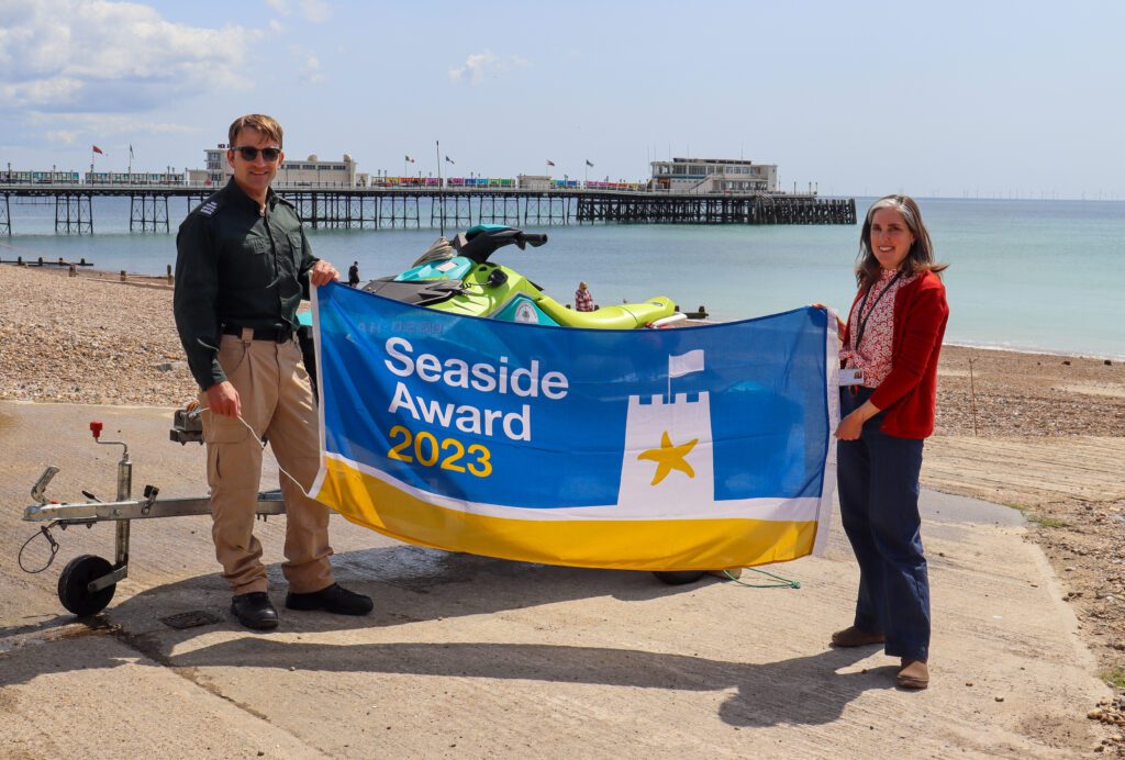 Rob Dove, Senior Coastal Warden, pictured with Cllr Vicki Wells holding the 2023 Seaside Award flag